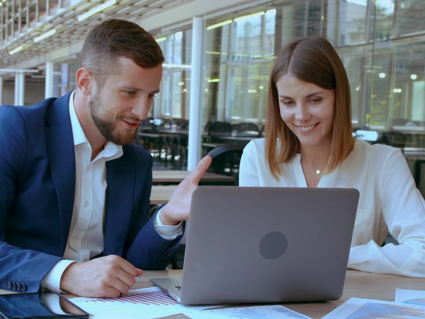 Two colleagues discussing work together at a laptop